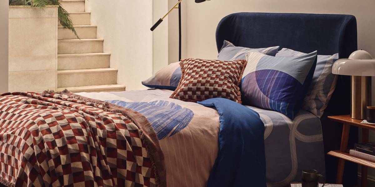 Manželská postel s modrým vzorovaným ložním prádlem. Prohlédnout všechny domácí potřeby